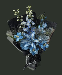 Full dyed blue lilies with blue delphinium, gerbera, eryngium, blue star flowers, silver mist foliage, and black wrapping