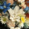 Close-up detail of double cream lilies with a dyed blue tulip, champagne gerbera and carnations, orchids, rust chrysanthemums, and autumn foliage