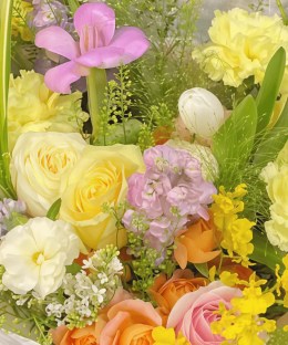 Close-up detail of yellow garden roses, orange spray roses, purple stock, pink freesia, oncidium, blue tweedia, and pale delphinium