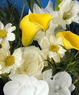 Close-up detail of yellow calla lilies and craspedia with white roses, gladiolus, phalaenopsis orchids, and blue wrapping