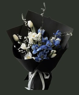 Full white tulips and dyed blue marbled tulips with delicate white flowering branches in black wrapping