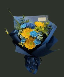 Full three yellow sunflowers with dyed blue carnations, deep-blue delphinium, pale-blue flowers, yellow accents, and airy grass