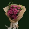 Mauve and berry-toned roses gathered in a natural-paper bouquet with fresh foliage.