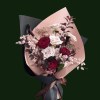 Blush and burgundy roses with airy accent flowers in layered pink and black wrapping.