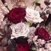 Close-up of burgundy and blush roses with delicate pale accent flowers.