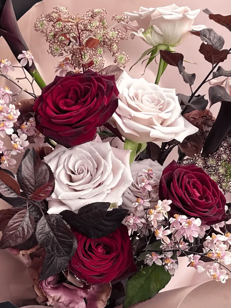 Close-up of burgundy and blush roses with delicate pale accent flowers.