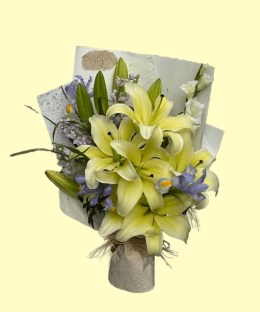 Full cream-yellow perfume lilies, lavender irises, ivory and lilac stock, white seasonal flowers and fresh green foliage