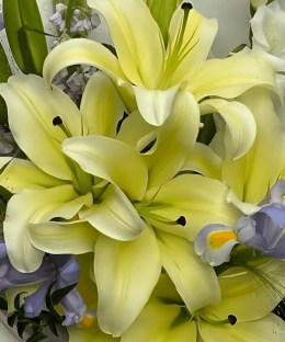Close-up of cream-yellow perfume lilies, lavender irises, ivory and lilac stock, white seasonal flowers and fresh green foliage