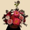Full coral peonies, blush garden roses, pink-orange dahlias, scabiosa, dark carnations, and burgundy foliage in a basket