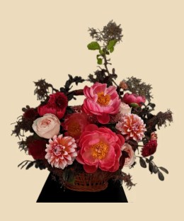 Full coral peonies, blush garden roses, pink-orange dahlias, scabiosa, dark carnations, and burgundy foliage in a basket