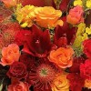 Close-up of red lilies, red roses, and orange pincushion protea in the Crimson Celebration Grande Bouquet