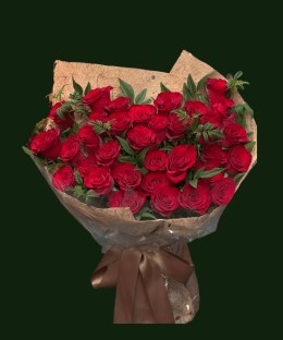 Red roses with loose green foliage in warm natural paper wrapping