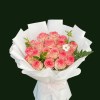 Peach-pink roses with greenery and white accents in sculptural white wrapping