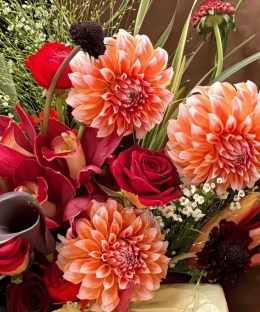 Close-up of apricot dahlias, deep-red roses, and burgundy cymbidium orchids in the Ember Dahlia & Burgundy Orchid Bouquet