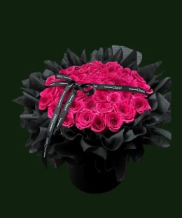 Fuchsia Floyd rose arrangement in a black basket with dark wrapping and a black ribbon.