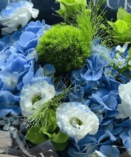 Close-up detail of blue hydrangea and dyed lisianthus with Green Trick dianthus, green anthurium, blue star flowers, and airy grass