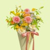Full pink pompon dahlias, cream roses, orange ranunculus, yellow calla lily, oncidium, and blue tweedia