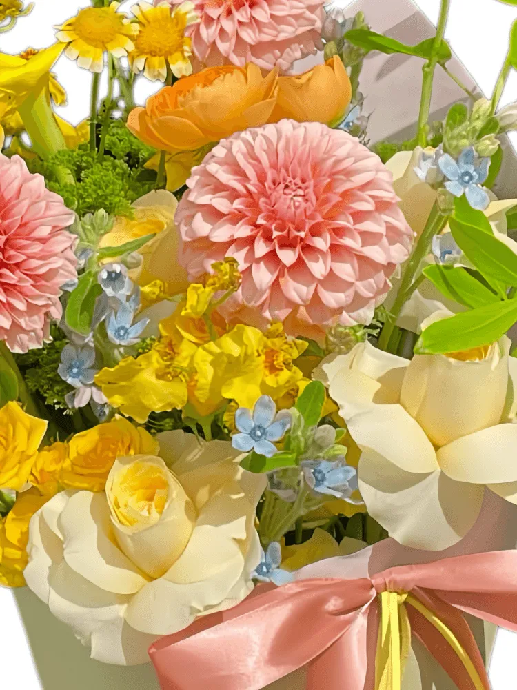 Close-up detail of pink pompon dahlias, cream roses, orange ranunculus, yellow calla lily, oncidium, and blue tweedia