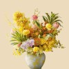 Full yellow cymbidium, peach ranunculus, blush phalaenopsis, pincushion protea, oncidium, berries, and striped foliage in porcelain