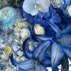 Close-up of dyed cobalt lilies, blue hydrangea, marbled roses, pale orchids, chrysanthemums, eryngium, and yellow craspedia in porcelain