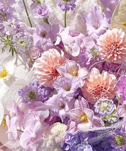 Close-up of peach dahlias, lavender gladiolus, hydrangea, white phalaenopsis, pale anthurium, and purple scabiosa