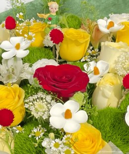 Close-up detail of red yellow and cream roses, Green Trick dianthus, white ranunculus, meadow flowers, and a Little Prince figure