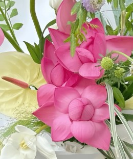 Close-up detail of pink lotus blooms and buds with pale anthurium, white lily, lilac scabiosa, and flowing grasses