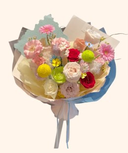 Full pink gerbera, red and cream roses, green ranunculus, button mums, dianthus, and blue accents