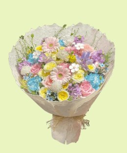 Full pink garden roses, blue hydrangea, purple stock, yellow ranunculus, sweet pea, and blue tweedia in a pastel bouquet