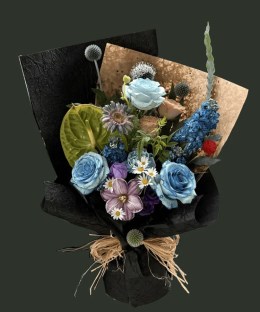 Full dyed blue roses with green anthurium, mauve gerbera, striped tulip, blue delphinium, thistles, daisies, and red gomphrena