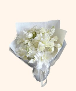 Full white Oriental lilies, white roses, ivory stock, and green foliage in cool grey wrapping