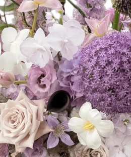 Close-up of giant purple allium with black and blush calla lilies, pale orchids, dusty roses, lisianthus, and misty grass