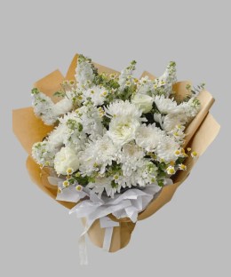 White chrysanthemums, stock, lisianthus, carnations, and feverfew in kraft wrapping