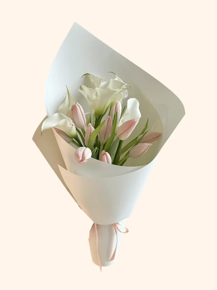 Full blush-pink tulips, white calla lilies, natural green leaves, and pale mint wrapping