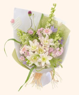 Full blush double lilies, pink gerbera, pale delphinium, white tulip, purple flowers, and misty green grass