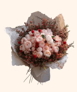 Full blush peonies, red globe flowers, coral waxflower, dark foliage, and cream wrapping