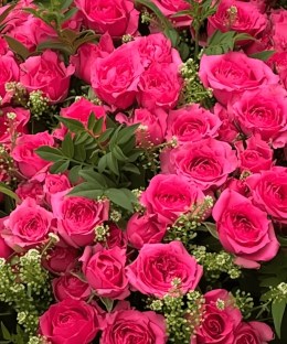 Close-up detail of pink roses, greenery, and filler flowers in a basket arrangement