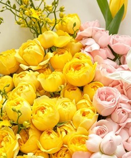 Close-up of yellow garden roses, blush spray roses, yellow oncidium, yellow tulip, and white bulb flowers