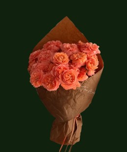 Soft tangerine roses arranged in warm brown paper wrapping