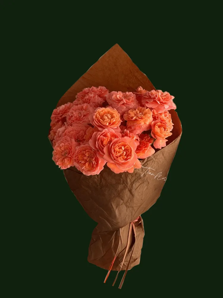 Soft tangerine roses arranged in warm brown paper wrapping