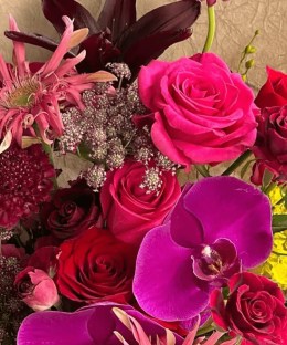 Close-up of magenta phalaenopsis orchids, red roses, and pink gerbera in the Velvet Orchid Crimson Bouquet