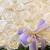 Close-up detail of white roses and purple bow on a flower basket