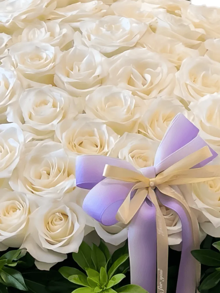 Close-up detail of white roses and purple bow on a flower basket